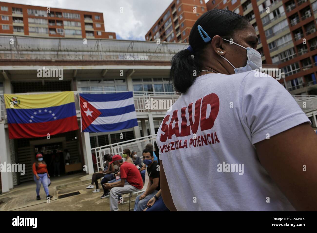 Caracas, Venezuela. 28th June, 2021. People wait outside an establishment with the Venezuelan and Cuban flags on its façade, where they are to receive the Cuban Corona vaccine, Abdala. The first shipment of vaccine from Cuba will give 10,000 people in Venezuela their first dose of the vaccine, according to Cuban authorities. Credit: Jesus Vargas/dpa/Alamy Live News Stock Photo