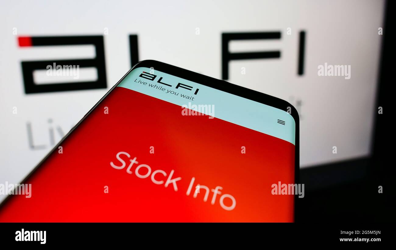 Mobile phone with webpage of American advertising platform company ALFI Inc. on screen in front of logo. Focus on top-left of phone display. Stock Photo