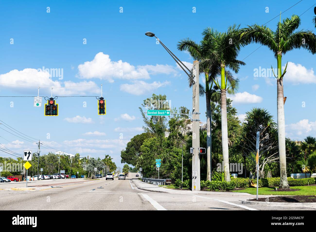 Palm trees on street road in Bonita Springs, Florida with sign for