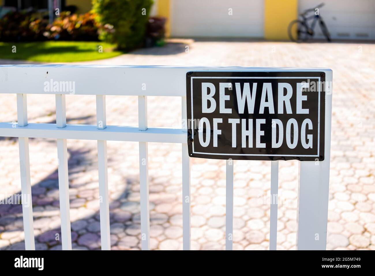 Beware of the dog sign on white fence gate railing in residential neighborhood house home in Hollywood, Florida Broward County North Miami Beach Stock Photo