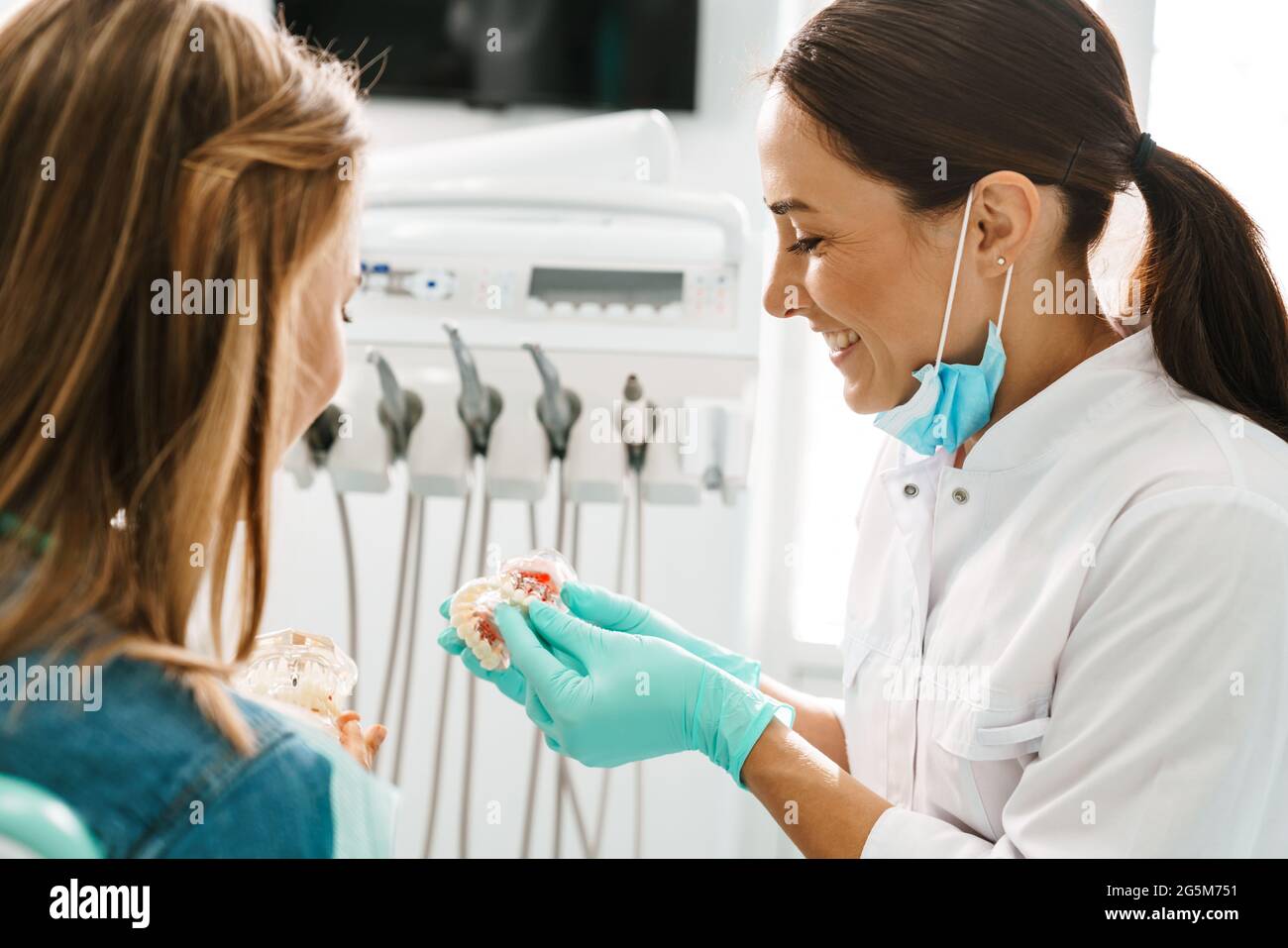 European mid happy dentist woman showing teeth imitation to her patient