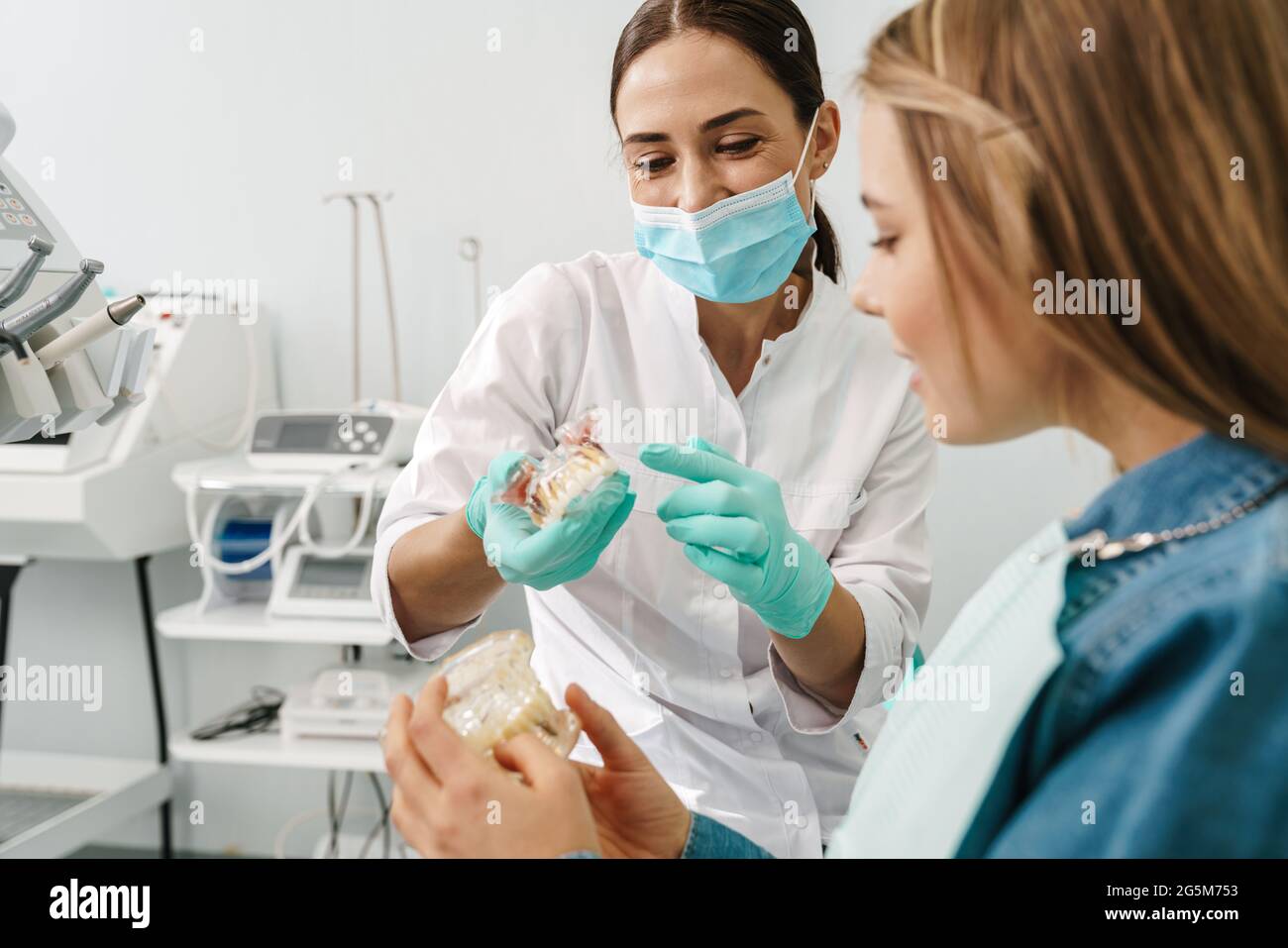 European mid happy dentist woman showing teeth imitation to her patient