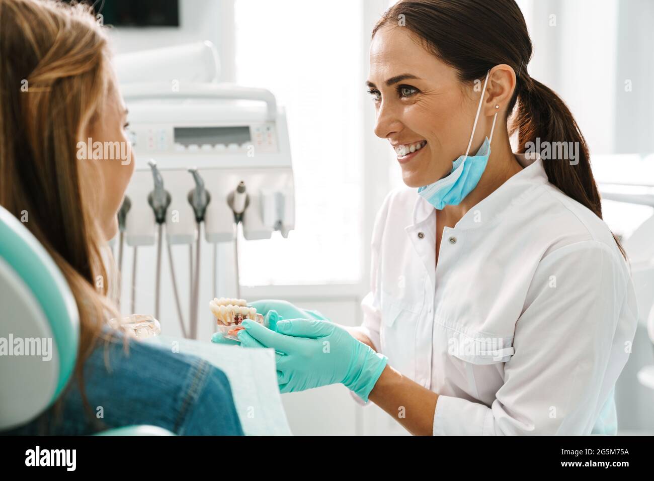 European mid happy dentist woman showing teeth imitation to her patient