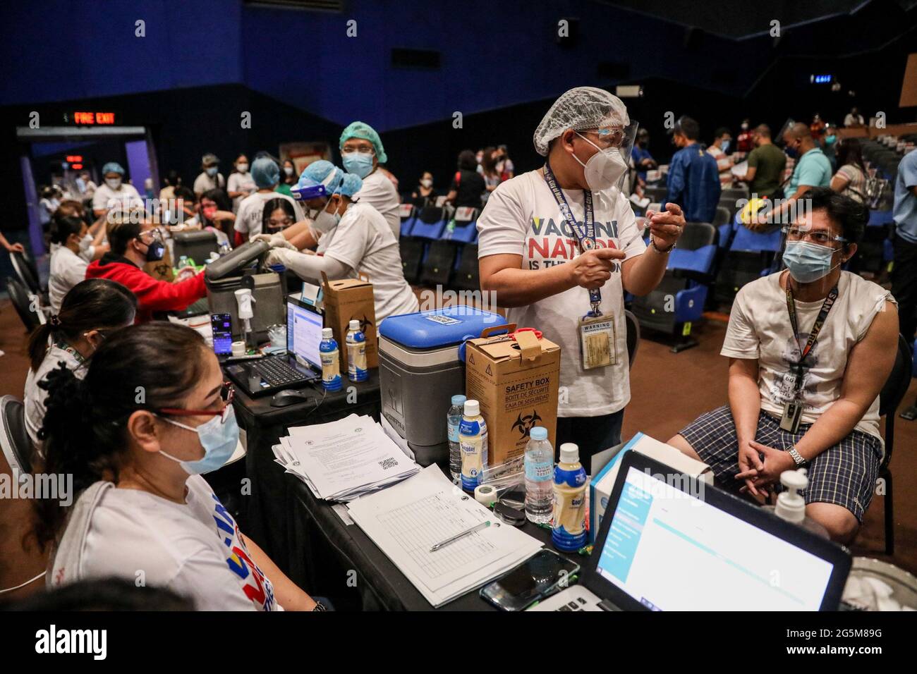 Health workers inoculate patients with the Sinovac COVID-19 vaccine inside a movie theater turned into a temporary vaccination site in Manila, Philippines. Stock Photo