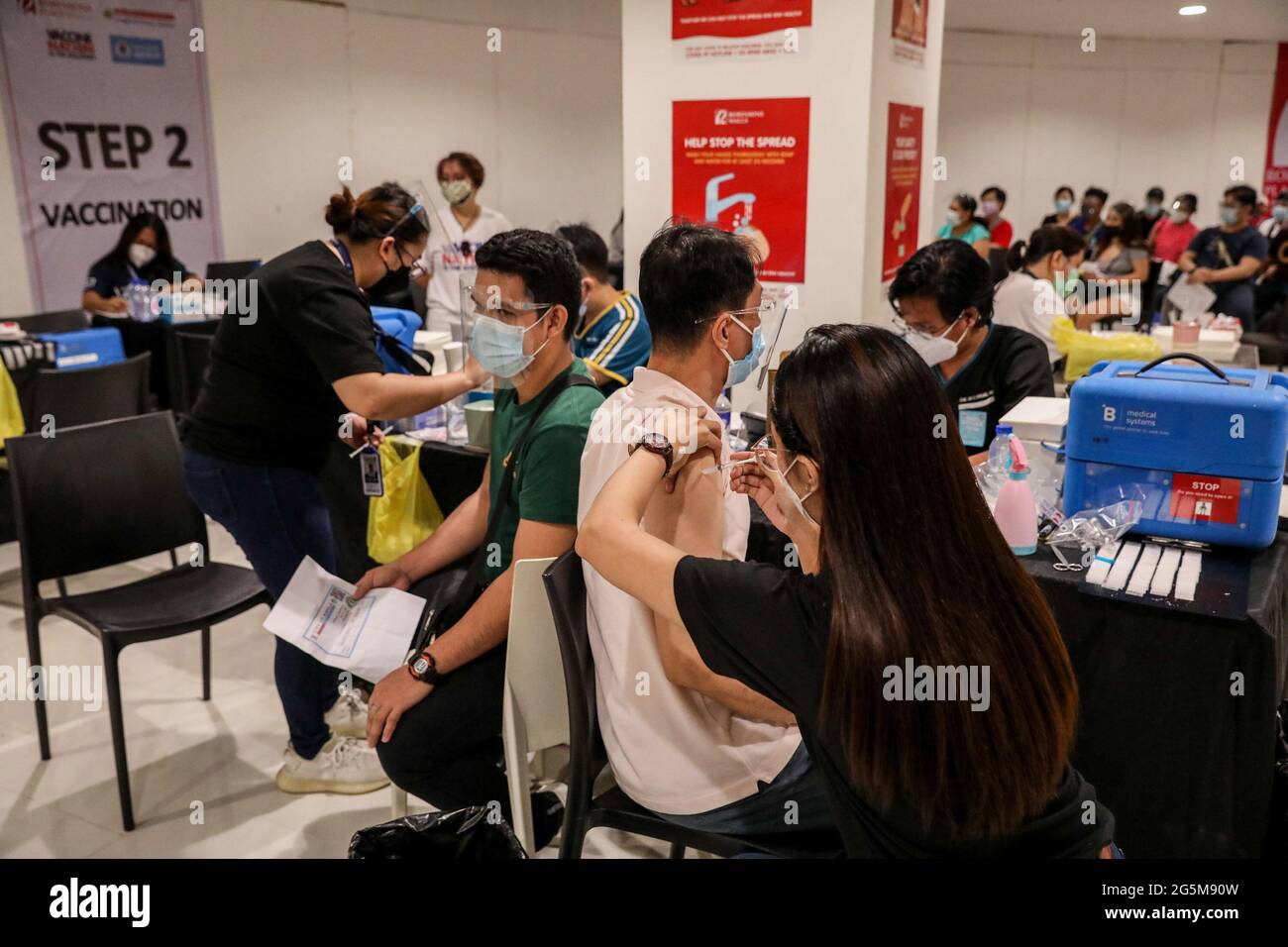 Health workers inoculate patients with the Sinovac COVID-19 vaccine inside a mall turned into a vaccination site in Manila, Philippines. Stock Photo