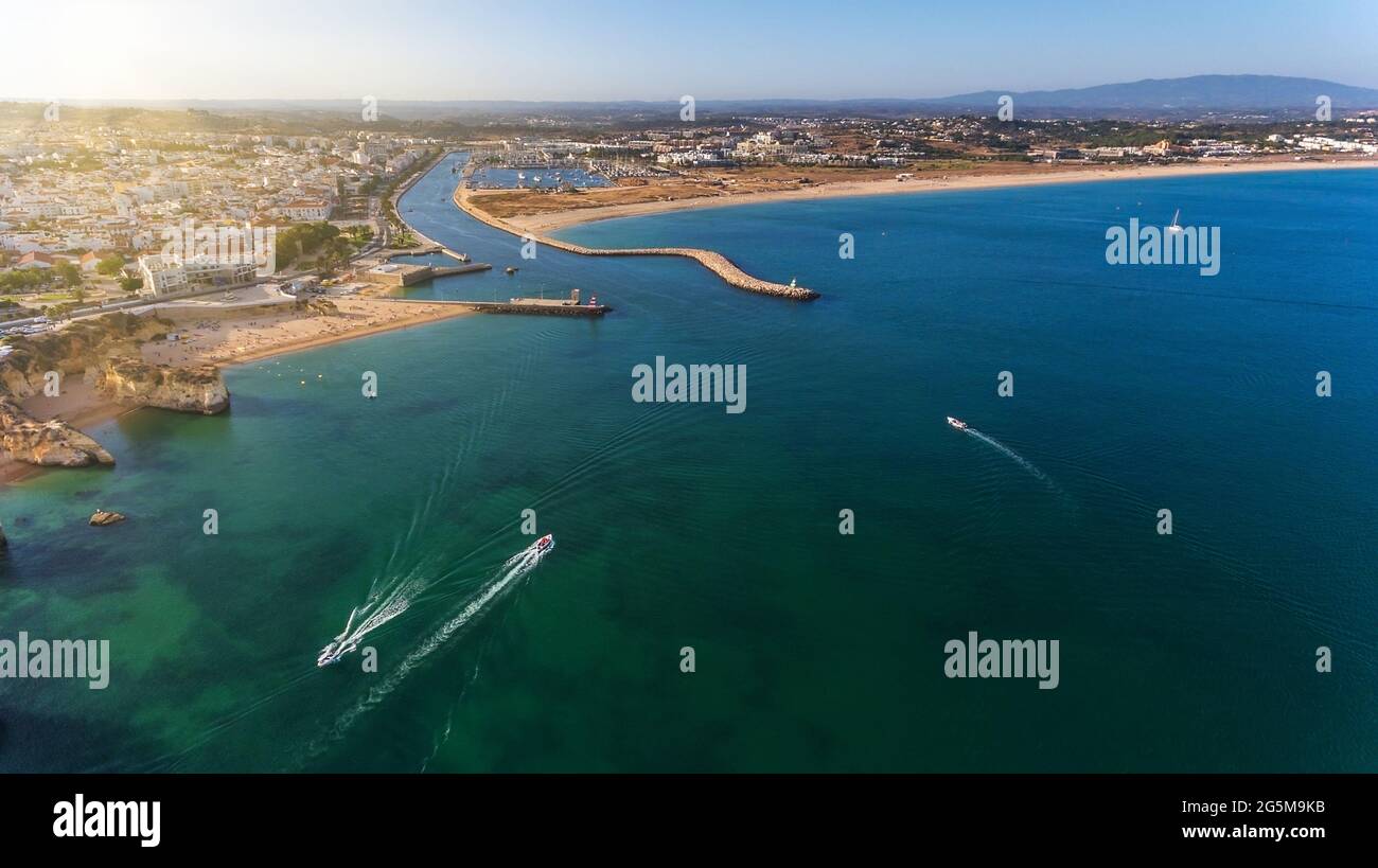Aerial view from the sky of the Portuguese coastline of the Algarve zone of Lagos city. Boats and ships are moving, Sunny day. Stock Photo