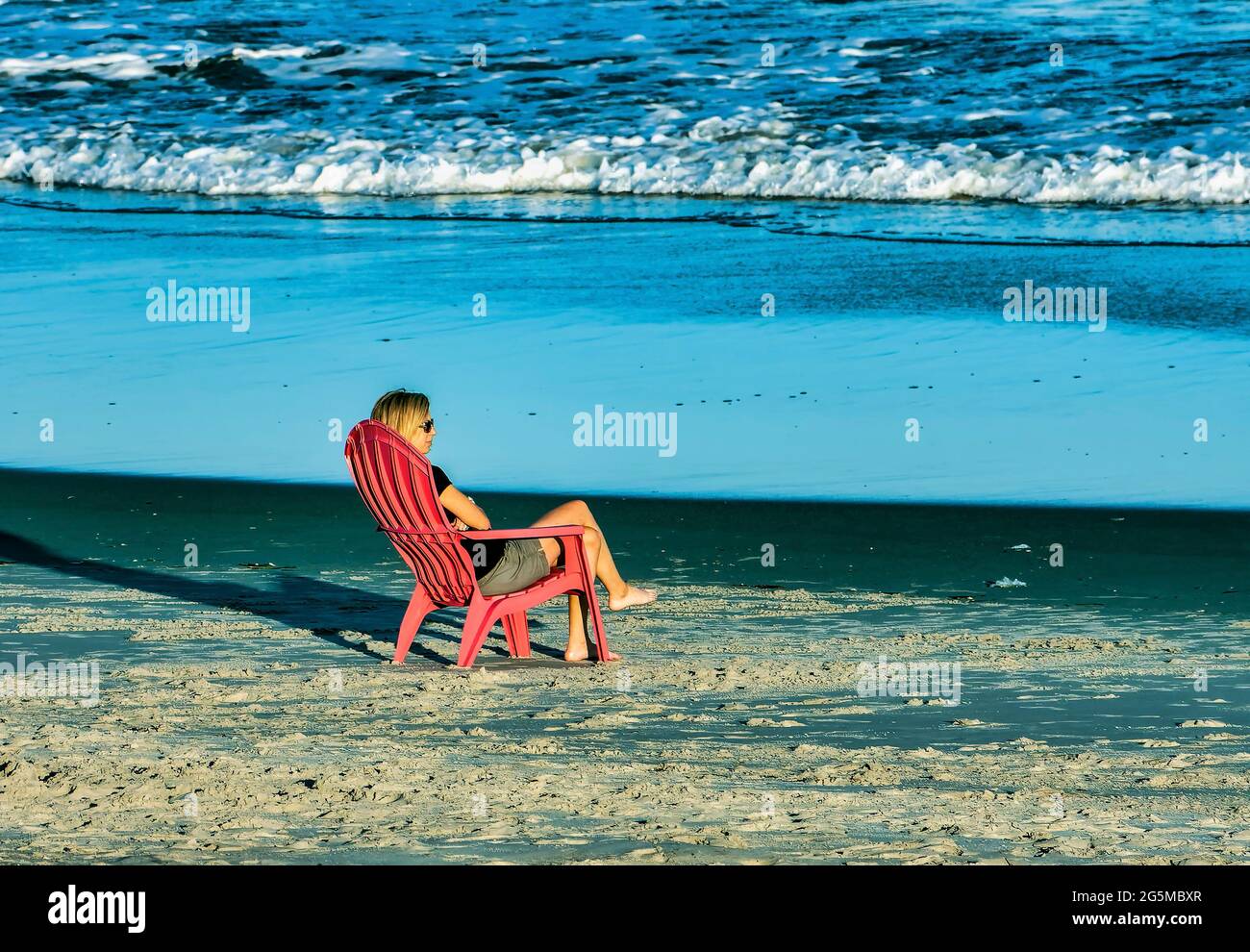 Woman alone sitting on the beach at the end of the day Stock Photo - Alamy