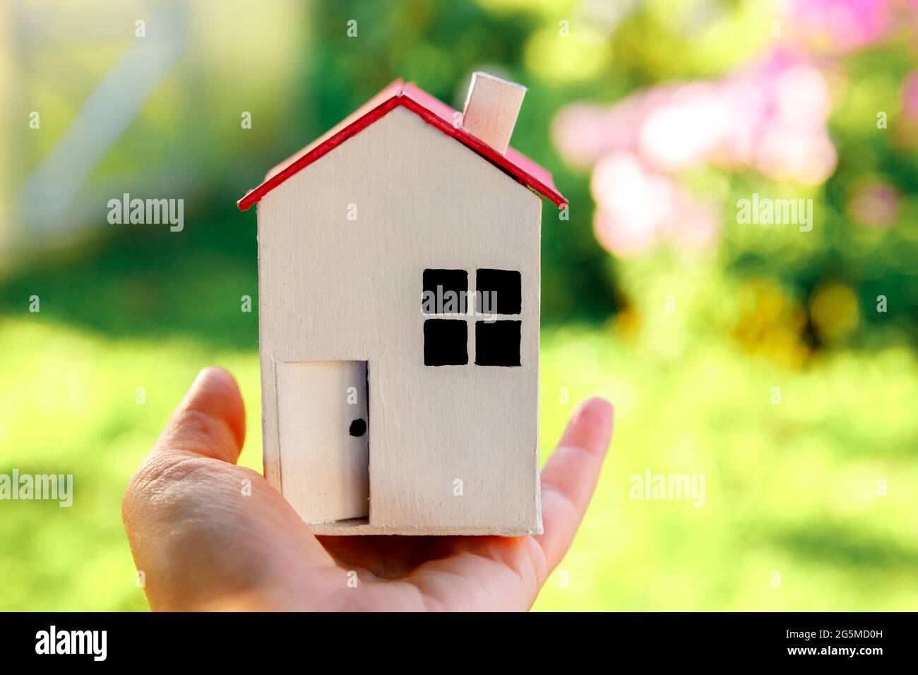 Miniature model house in female woman hand on green outdoor background ...