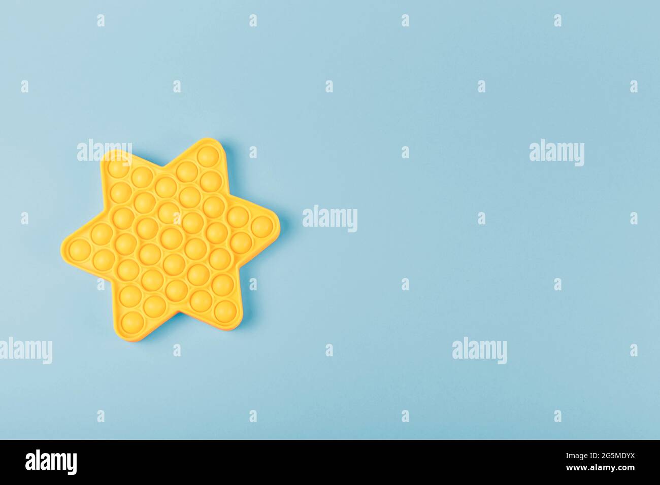 New silcone toy pop it in shape of star on the blue background. New sensory anti-stress toy for children and adult. Copy space. Flat lay. Stock Photo