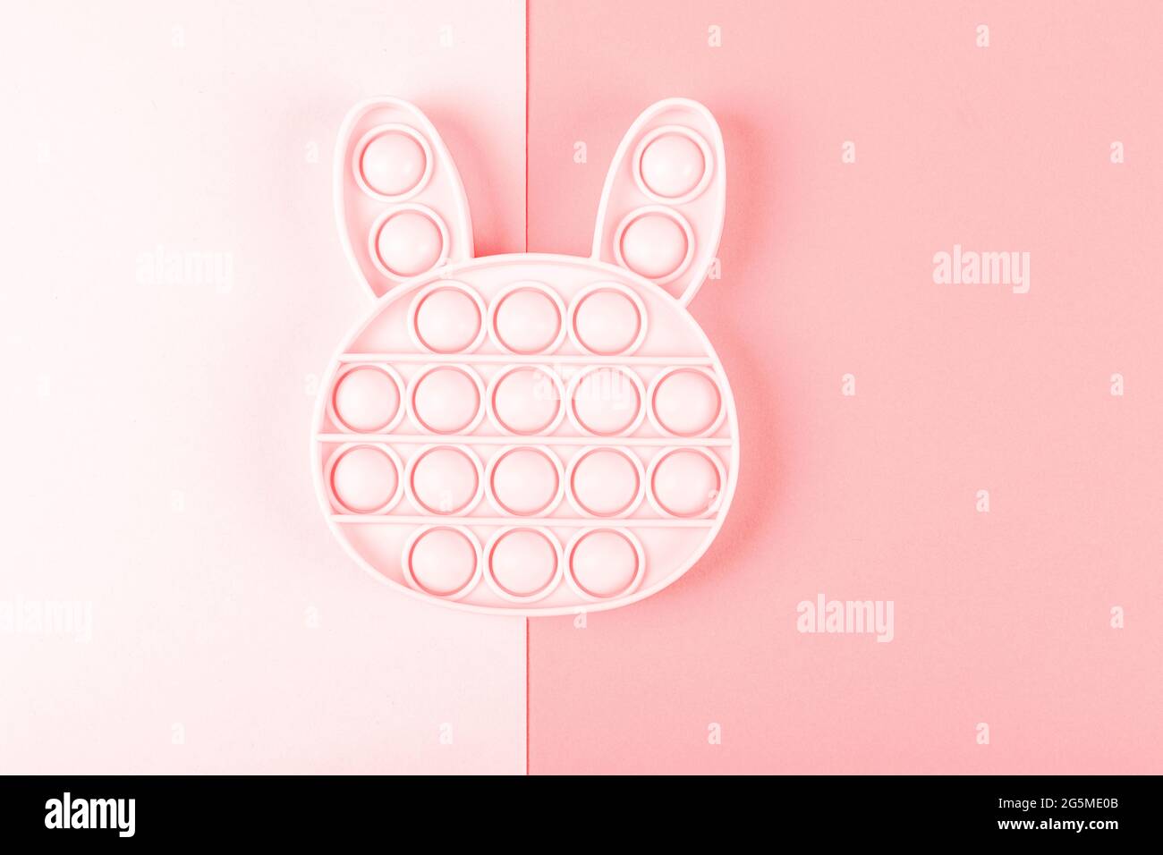 New silcone toy pop it in shape of bunny on the pink background. New sensory anti-stress toy for children and adult. Copy space. Flat lay. Stock Photo