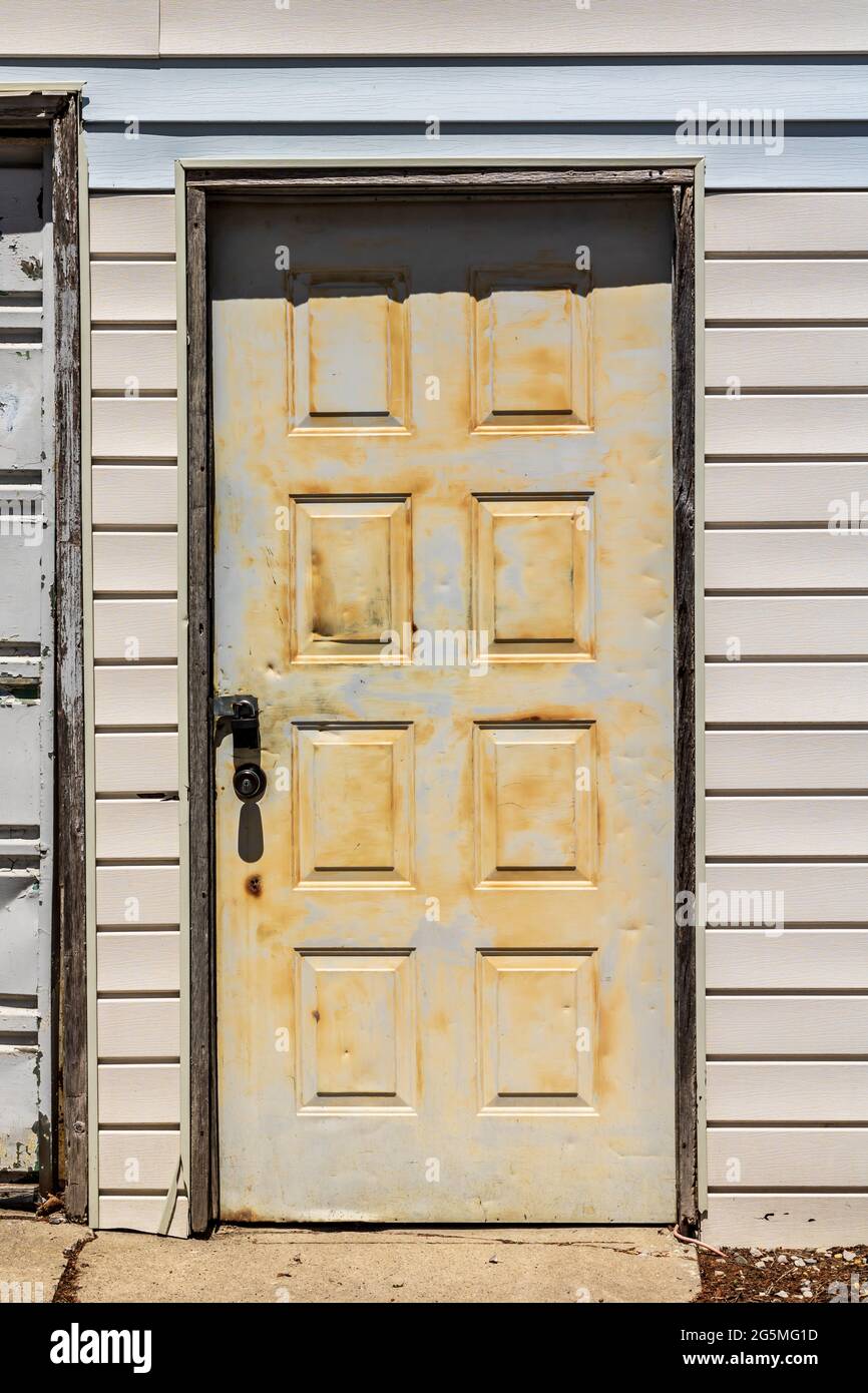 Old white aluminum door with padlock. Scratched, poor paint job