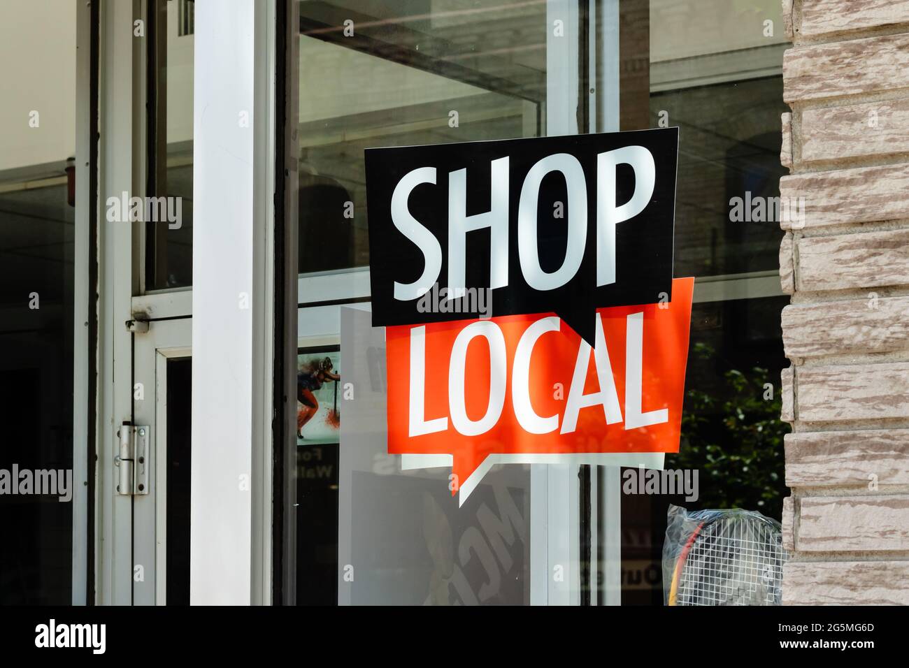 Shop Local sign in speech bubble on the front of a small town downtown store window. Stock Photo