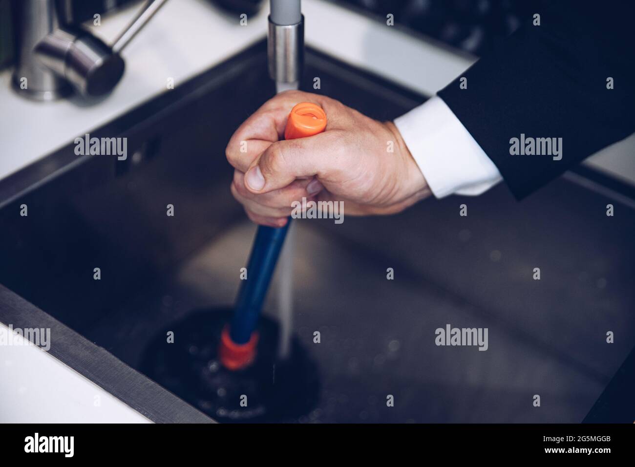 Male hands apply plunger to the kitchen sink. Stock Photo