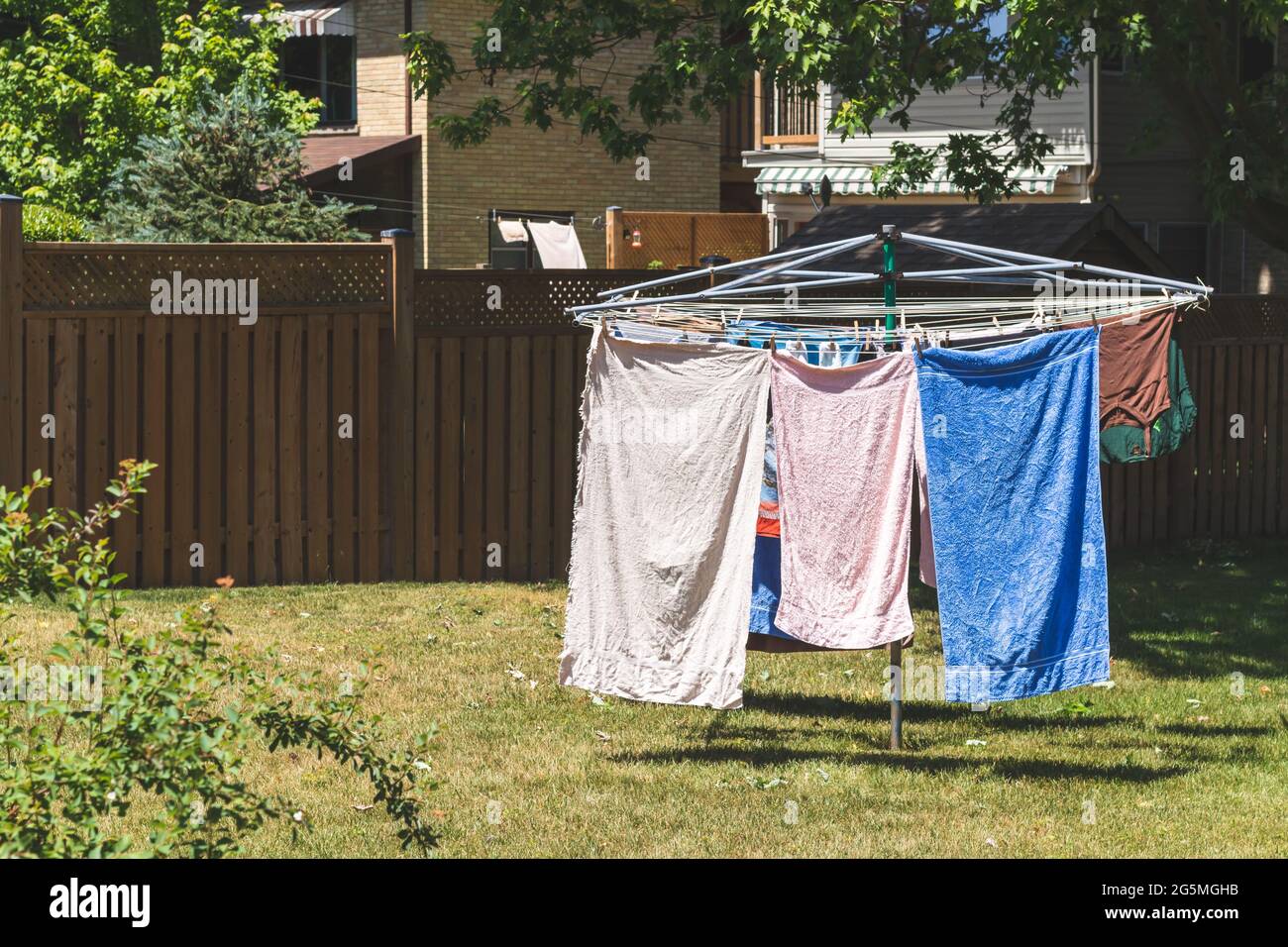 Metal outdoor clothes drying rack with towels and a shirt drying on it. On backyard lawn. Vintage filter. Stock Photo