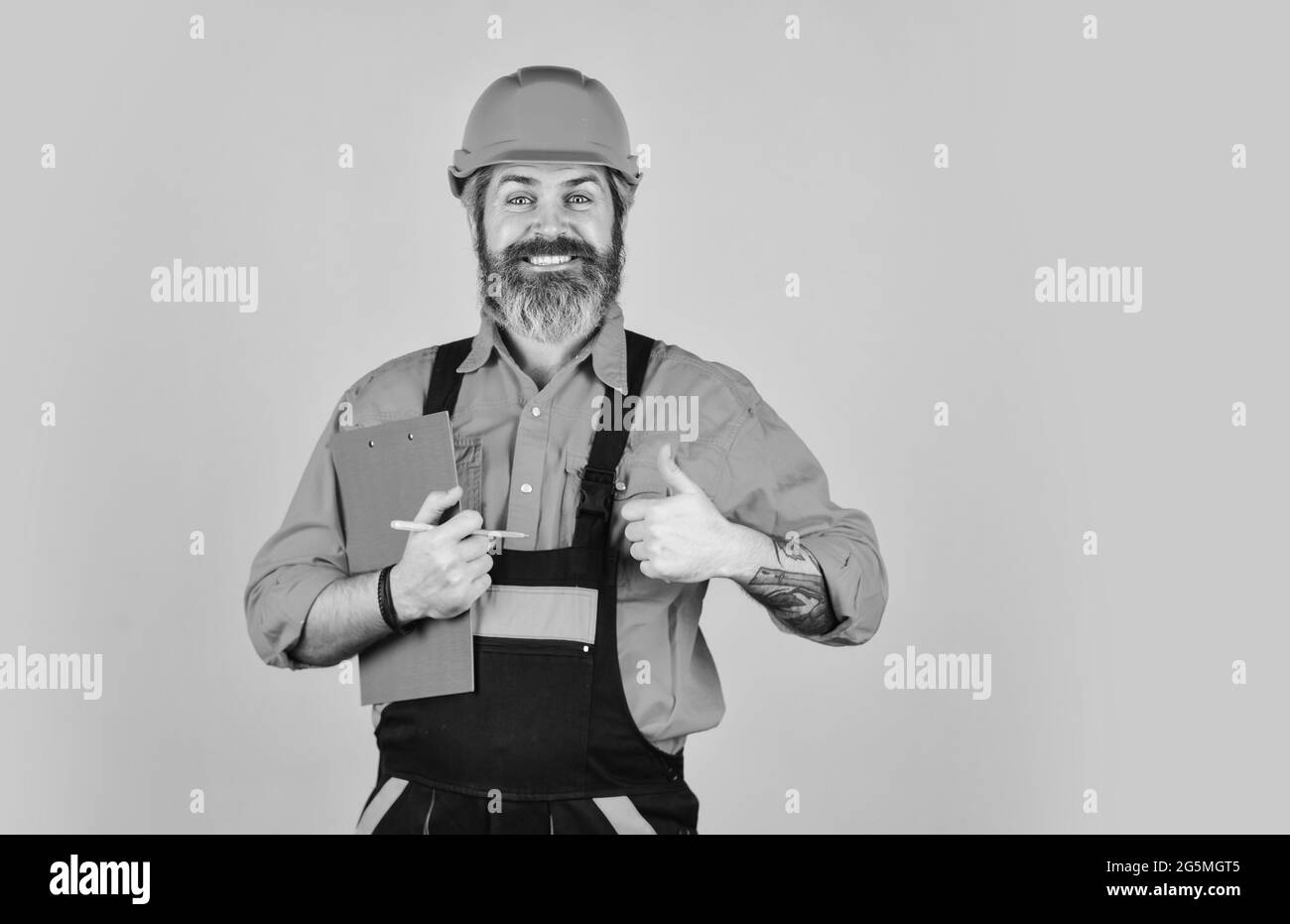 Control concept. Foreman with document. Delivering building materials. Man in hard hat holding clipboard looking information. Bearded storekeeper Stock Photo
