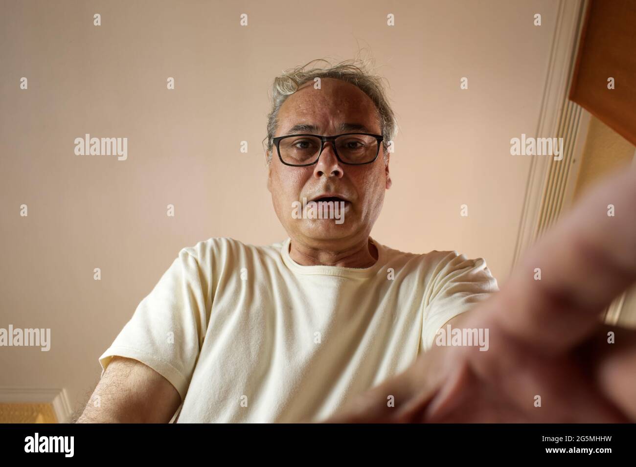 mature man with grey hair taking something from a drawer Stock Photo