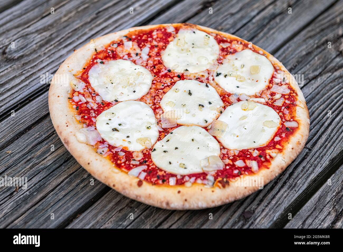 Fresh crust whole small pizza on table with melted mozzarella cheese and sprinkles and red tomato sauce closeup as Italian food cuisine Stock Photo