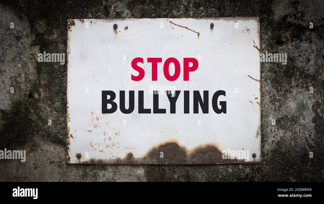Stop Bullying, words on a grunge metal board on wall. Stock Photo