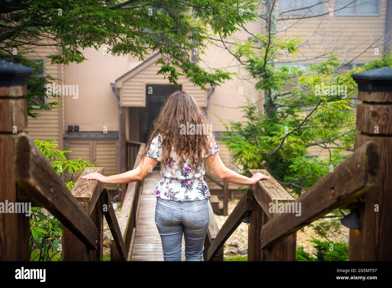 Wooden boardwalk entrance and woman person walking back to Wintergreen Resort, Virginia condo apartment condominium building for rent or rental proper Stock Photo