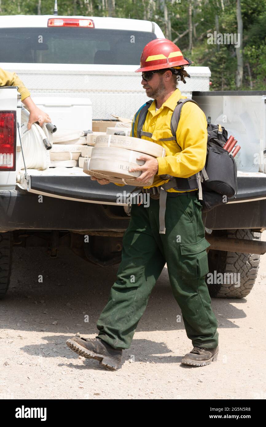 A firefighter carries water hoses to help put out a fire in the La Sal Mountains in Utah. Stock Photo