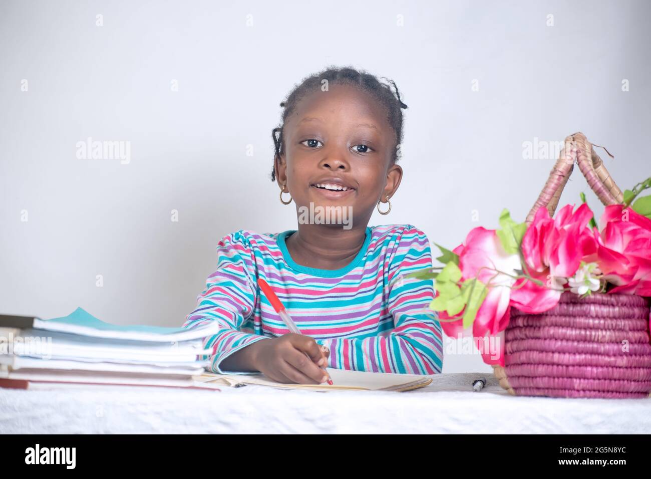 Close up education picture of an African girl child with woven hair style writing on a study table while having books and a basket of flowers by her Stock Photo - Alamy Close up education picture of an African girl child with woven hair style writing on a study table while having books and a basket of flowers by her Stock Photo - Alamy