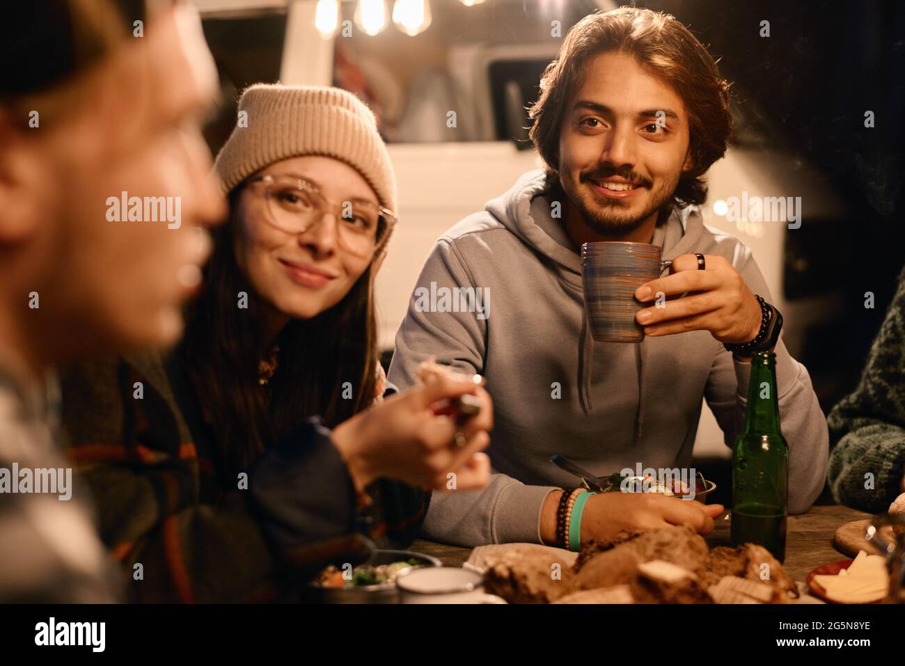 Group of young people sitting at the table and having dinner together outdoors Stock Photo