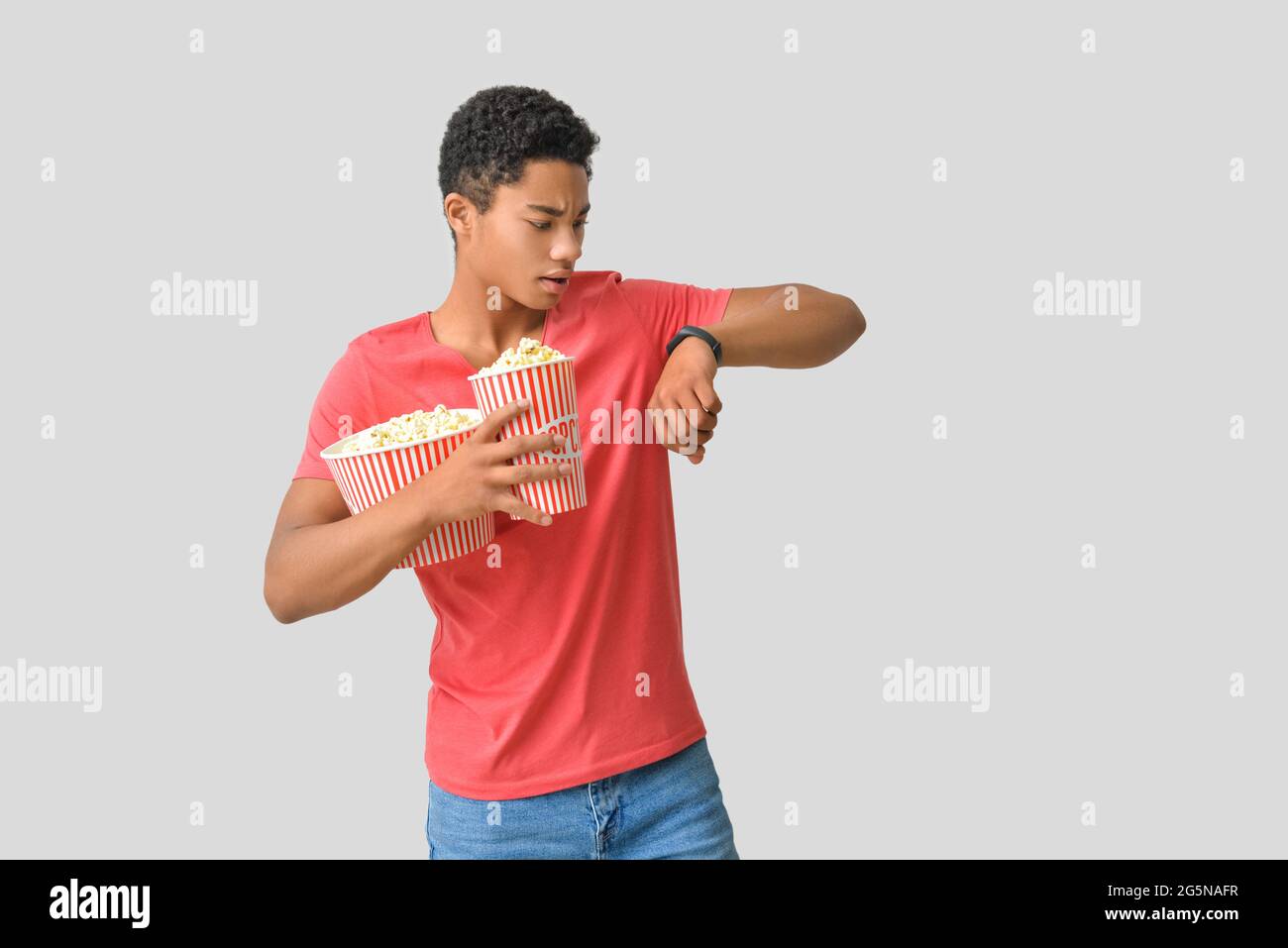 African-American teenager with popcorn on light background Stock Photo