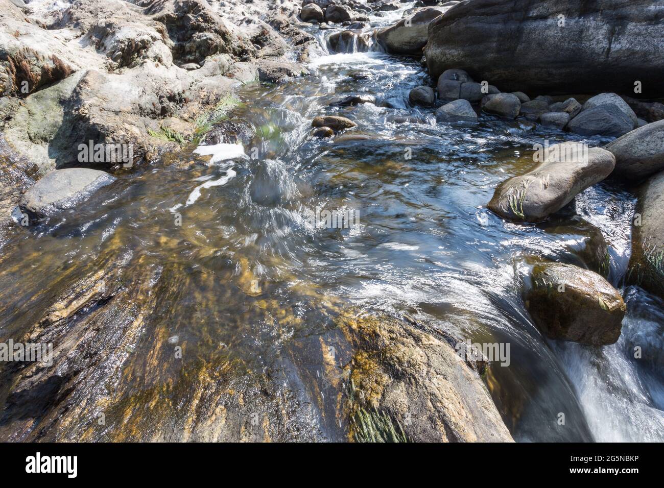 Mountain water flows between stones Stock Photo