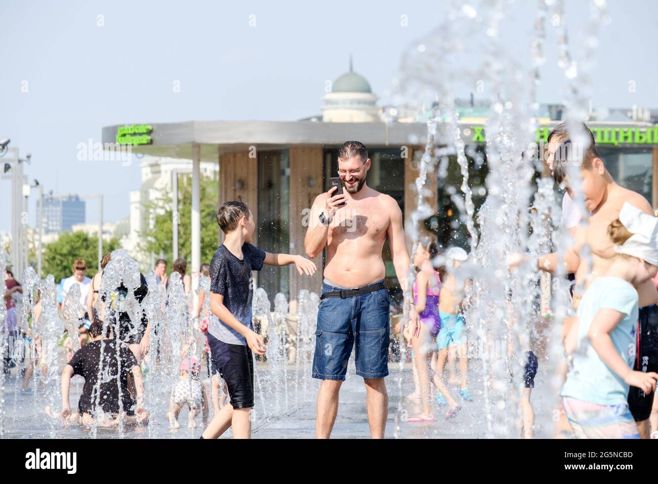 Moscow, Russia, June 26, 2021. Men and children bathe in the jets of the fountain in the Muzeon Park. Water entertainment for the townspeople on a hot Stock Photo