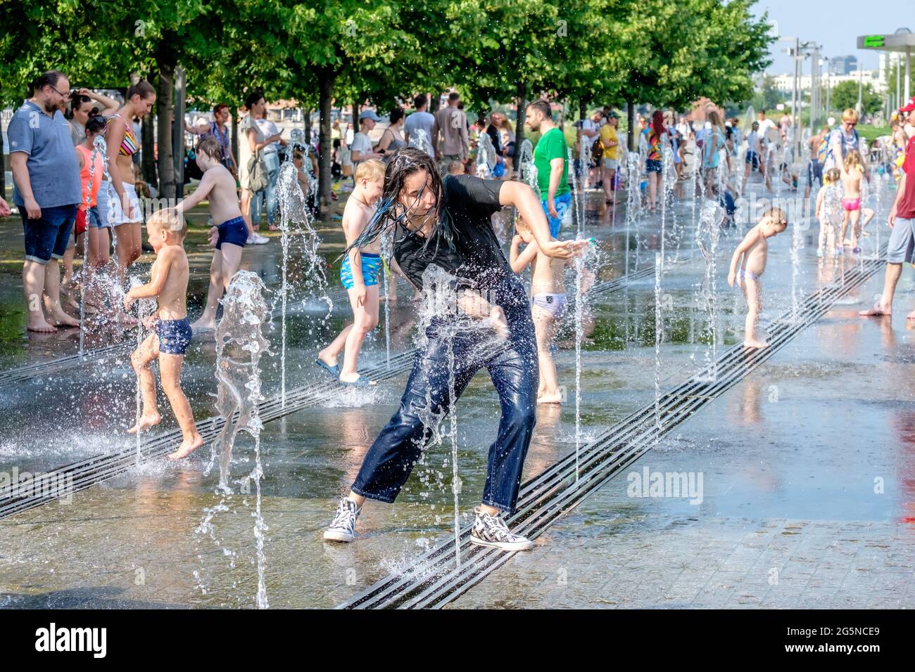 Moscow, Russia, June 26, 2021. Women, men and children bathe in the jets of the fountain in the Muzeon Park. Water entertainment for the townspeople Stock Photo
