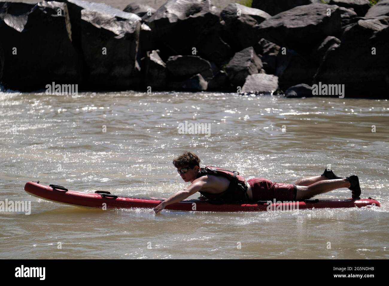 A lifeguard monitors the water as people cool off in the Sandy River by