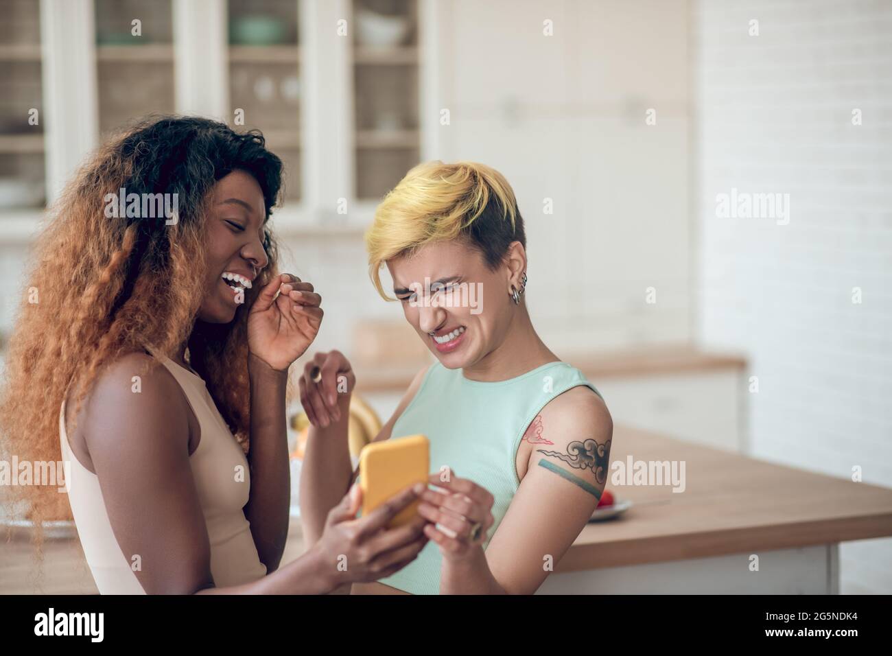 Two girlfriends looking into smartphone and laughing Stock Photo