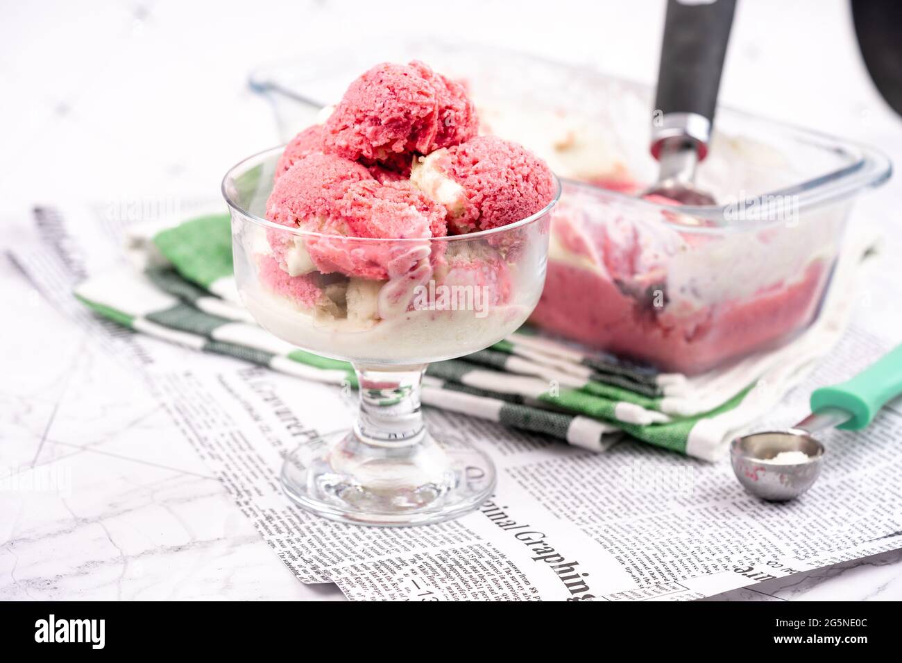 Strawberry frozen yogurt in glass bowl, ice cream balls, container with homemade sundae Stock Photo
