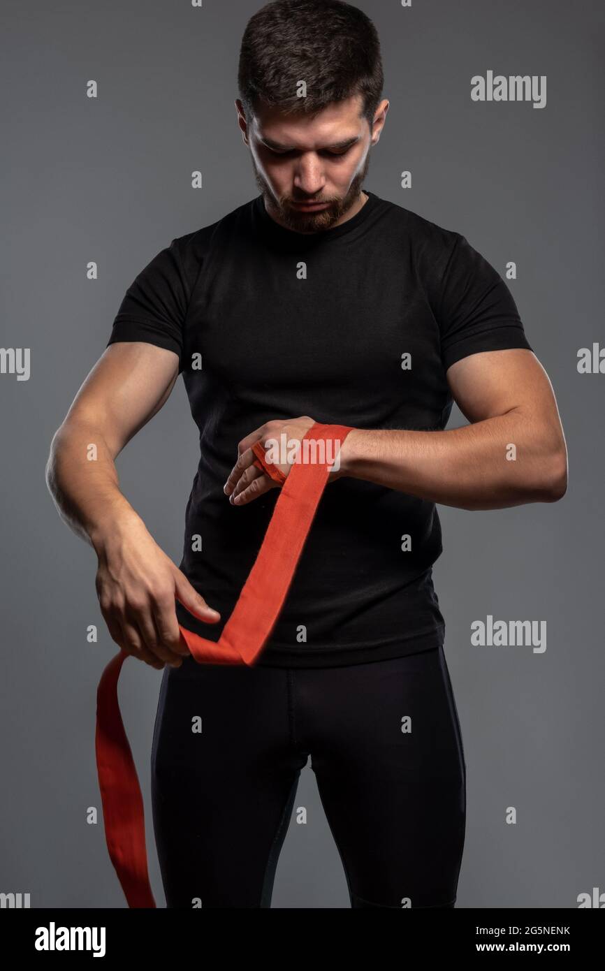Focused guy wrapping hands with boxing tape before fight Stock Photo