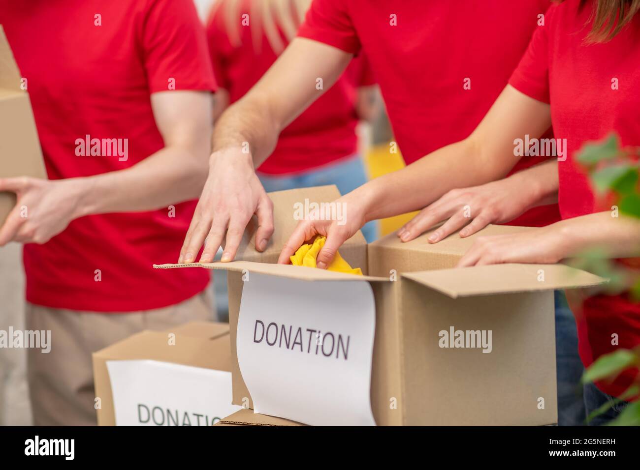 Volunteer hands carefully wrapping donation boxes Stock Photo - Alamy