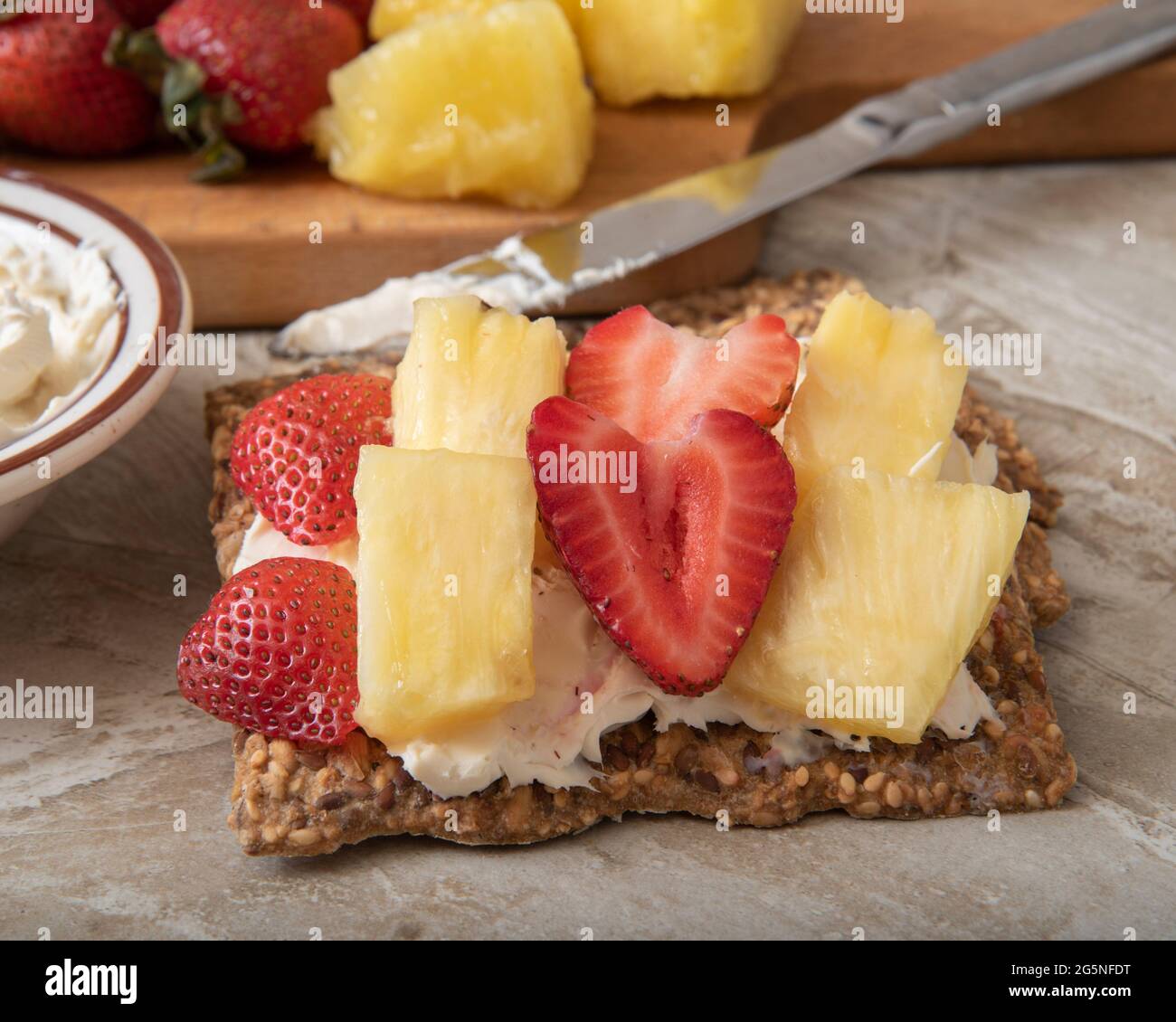 Gluten free crispbread with cream cheese, strawberries and pineapple for a healthy snack igh angle view Stock Photo