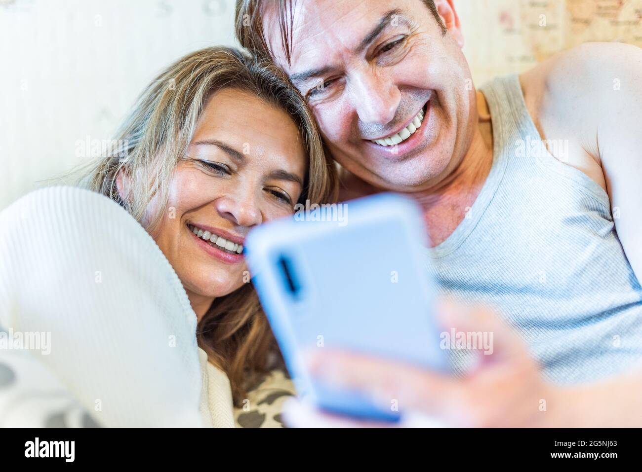 Happy middle-aged couple looking at mobile smiling. Stock Photo