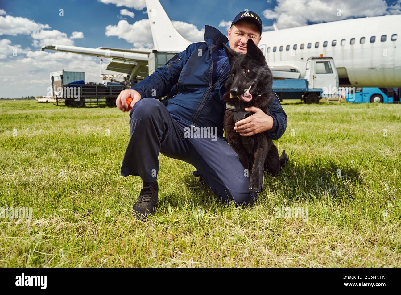 Male security officer hugging detection dog at airfield Stock Photo