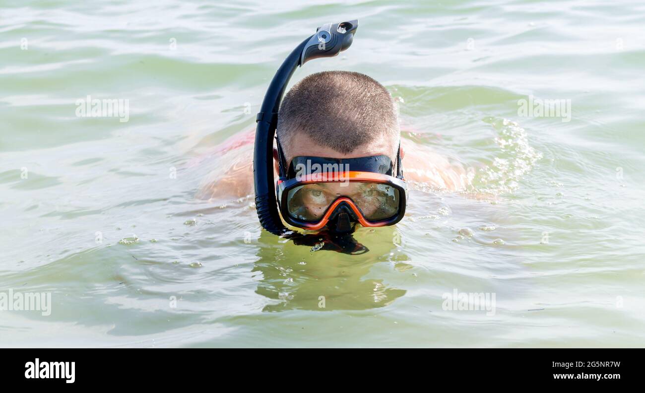 Man with snorkeling equipment: snorkel and scuba mask on the sea water Stock Photo