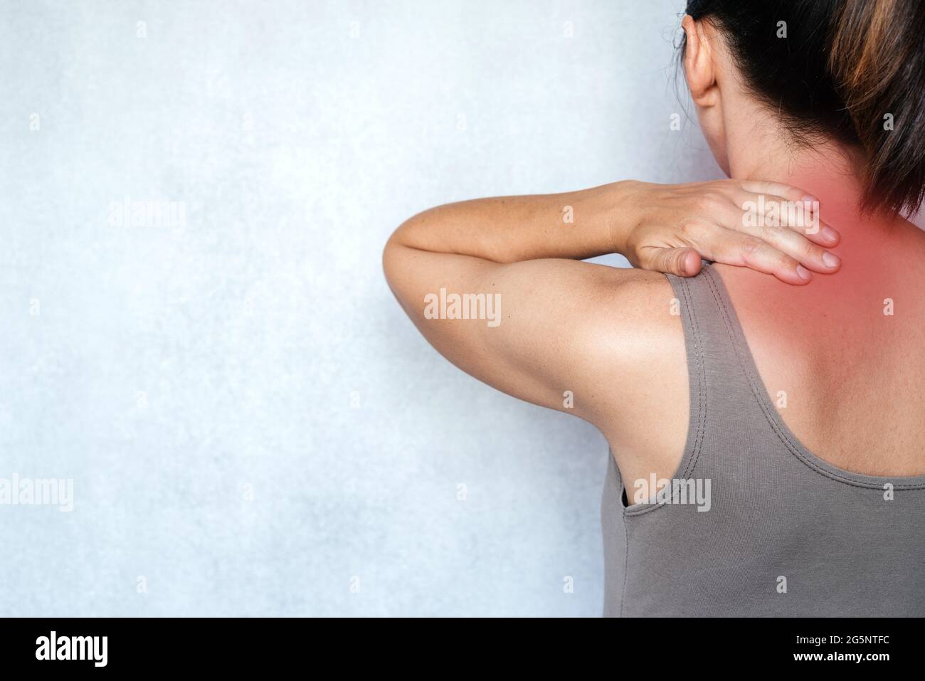 A woman suffering from neck pain and massaging her neck to releive pain ...