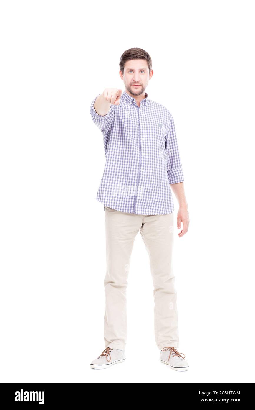 Vertical full length portrait shot of mature Caucasian man wearing blue checked shirt pointing finger at camera, white background Stock Photo