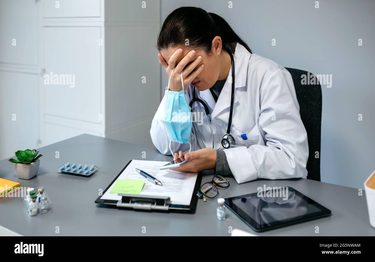 Worried female doctor with hands on face Stock Photo