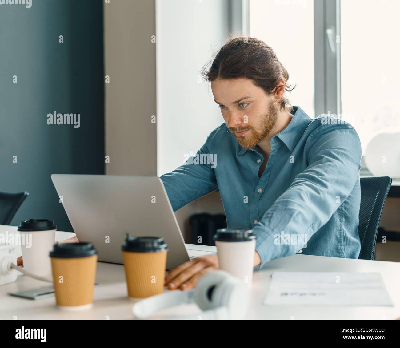 Stressed young male office worker trying to concentrate while working on laptop Stock Photo