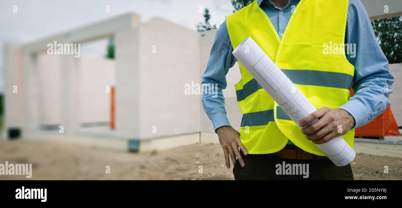 construction project architect with blueprint roll at building site. banner copy space Stock Photo
