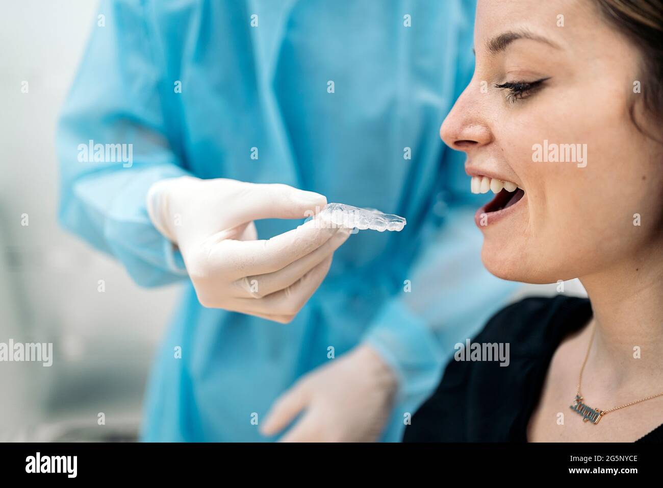 Dentist wearing face mask and special protective clothes explaining to