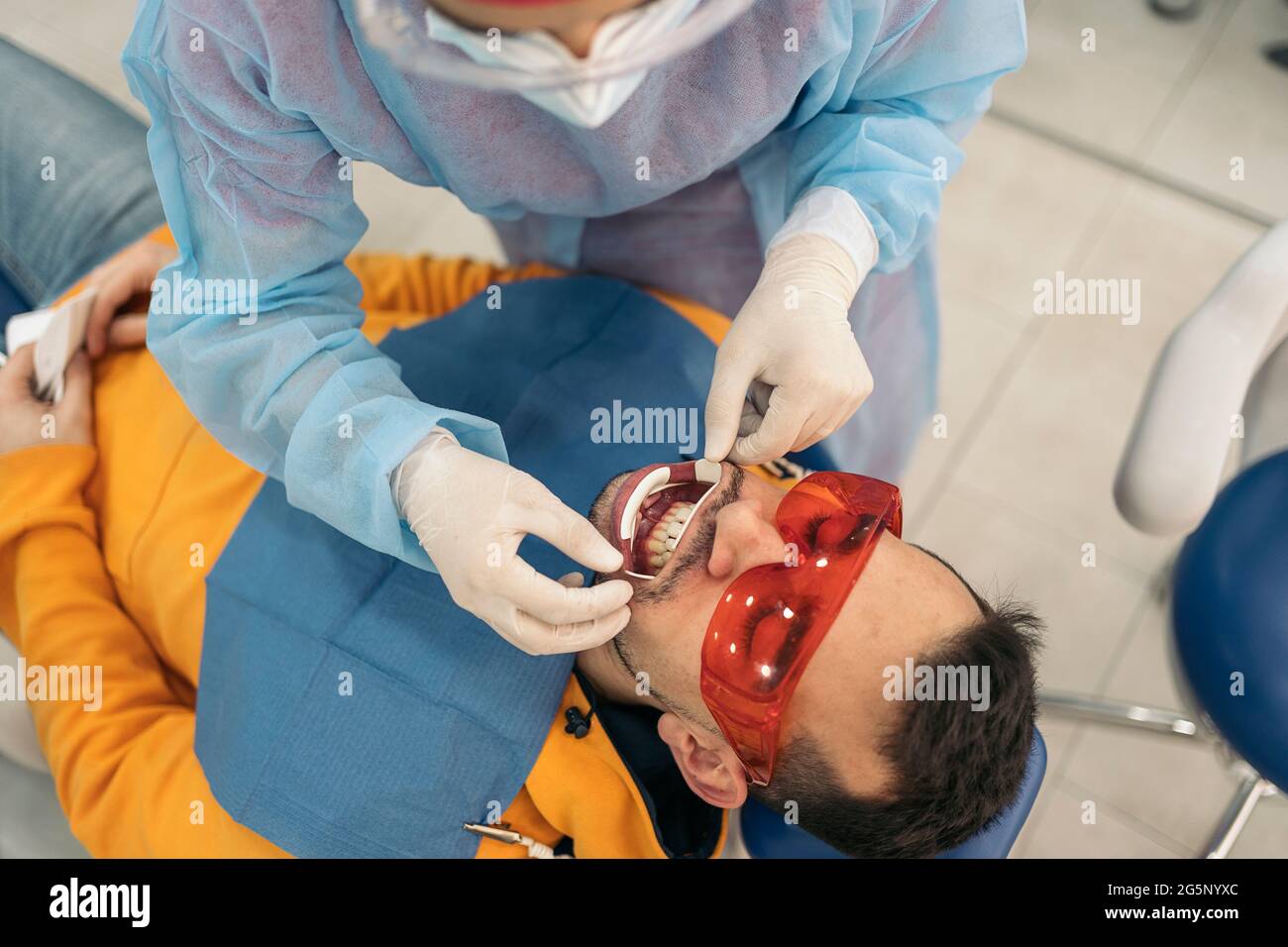 Man lying down in dental chair and wearing protective glasses using