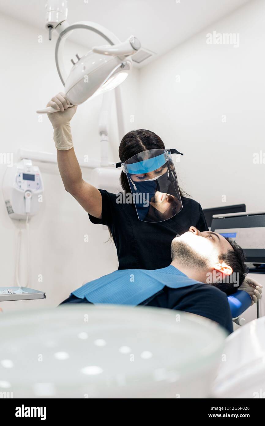 Female dentist wearing face shield isolation mask using light and