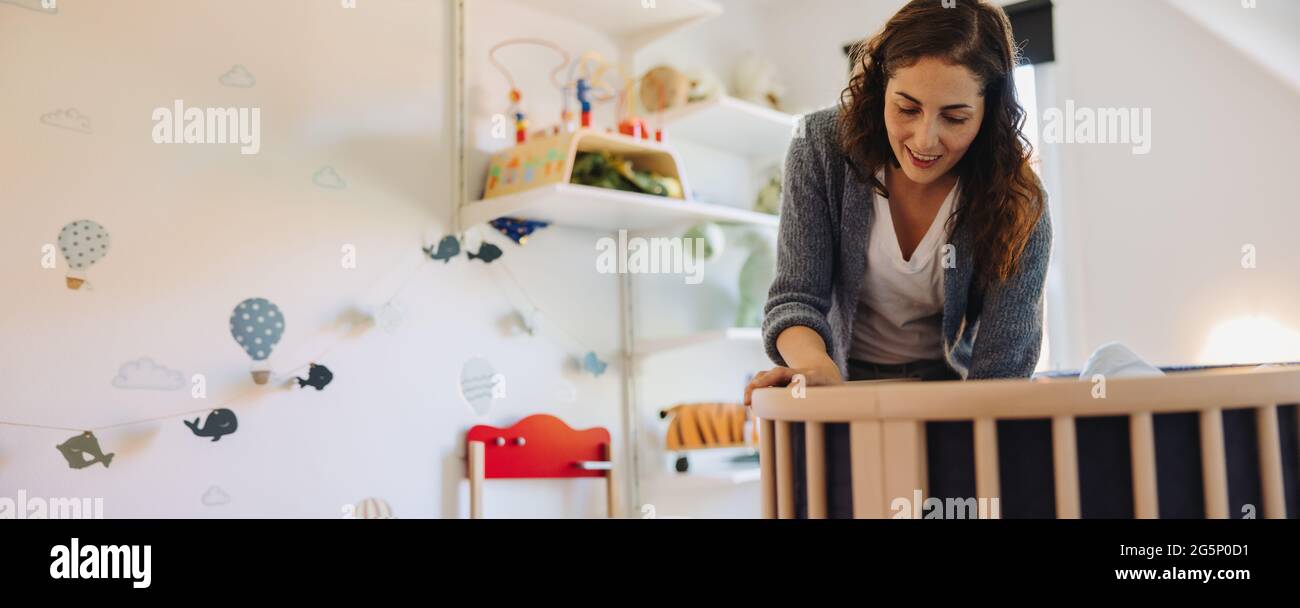 Mom training her baby to sleep in a crib. Woman admiring their baby in