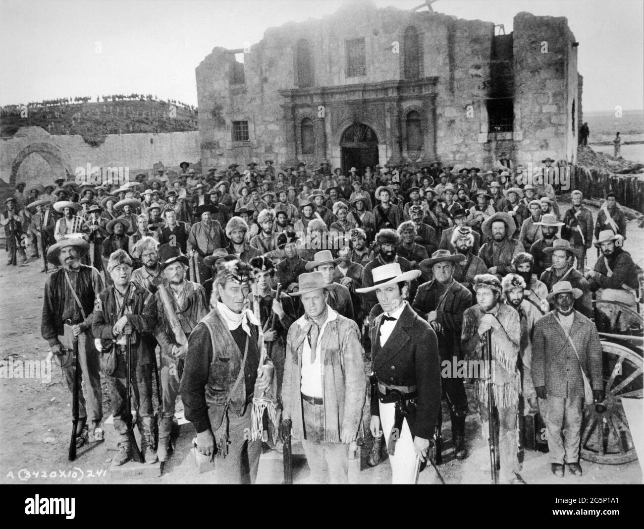 Cast Group photo with at front JOHN WAYNE as Colonel Davy Crockett RICHARD WIDMARK as Colonel Jim Bowie and LAURENCE HARVEY as Colonel William Barret Travis on set candid during filming of THE ALAMO 1960 director / producer JOHN WAYNE original screenplay James Edward Grant music Dimitri Tiomkin costume design Ron Talsky Batjac Productions / United Artists Stock Photo