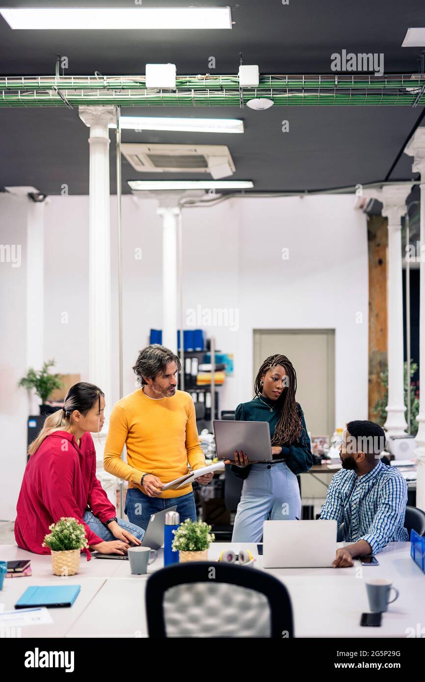 Diverse teamwork talking and using laptops in a modern bright office. Co-working concept Stock Photo